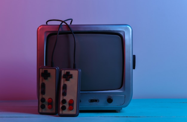 Alter TV-Empfänger mit Retro-Joysticks in rot-blauem Neonlicht. Retro-Spiele