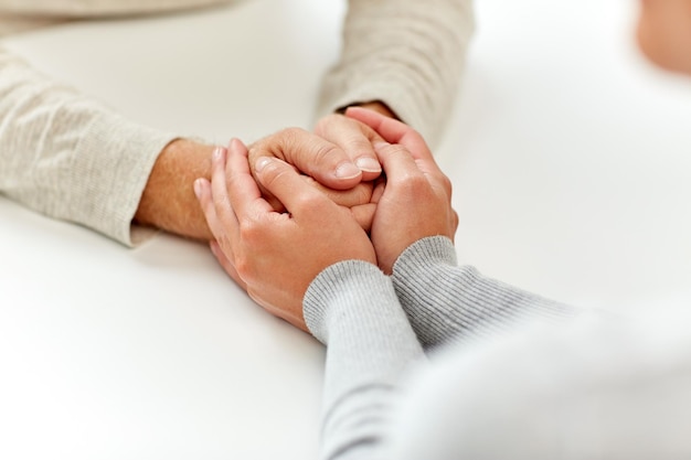 Alter, Unterstützung, Wohltätigkeit, Pflege und Menschenkonzept – Nahaufnahme eines älteren Mannes und einer jungen Frau, die Händchen halten
