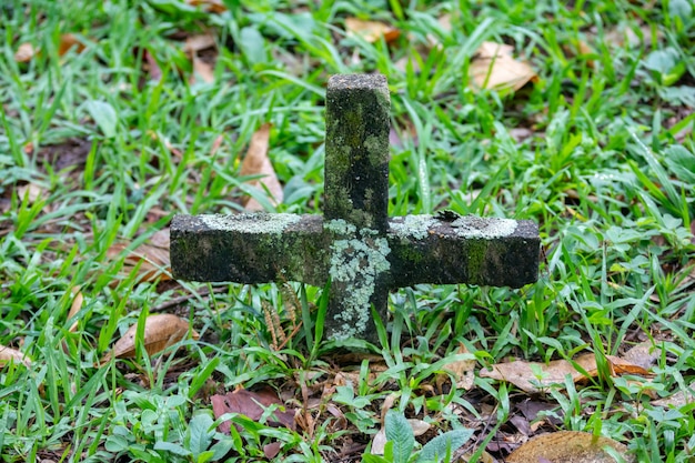 Alter vergessener und verlassener Friedhof mit Moos auf dem Kreuz