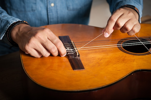 Foto alterando as cordas da guitarra clássica