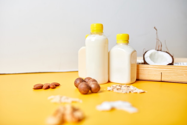 Alternative Arten von veganer Milch in Flaschen auf gelber Oberfläche, verschiedene vegane Milch und Zutaten auf pflanzlicher Basis, milchfreie Milch, alternative Milch