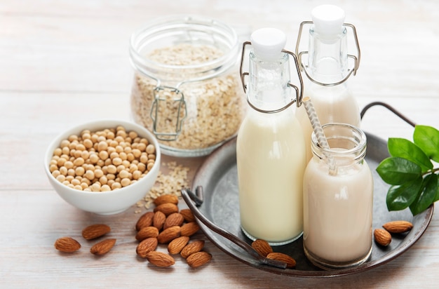 Alternative Arten von veganer Milch in Glasflaschen auf konkretem Hintergrund. Ansicht von oben