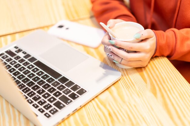 Alternative nicht erkennbare Person mit einem heißen Kaffee, die auf dem Computer im Internet surft