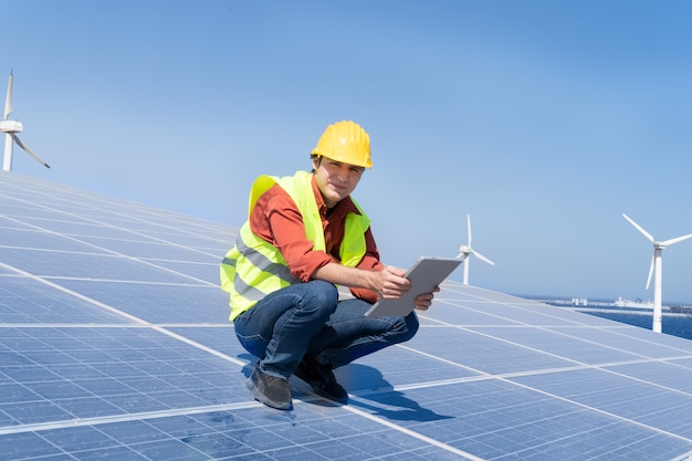 Alternatives Energiekonzept - Ingenieur sitzt auf Sonnenkollektoren, grüner Energie und umweltfreundlichem Industriekonzept