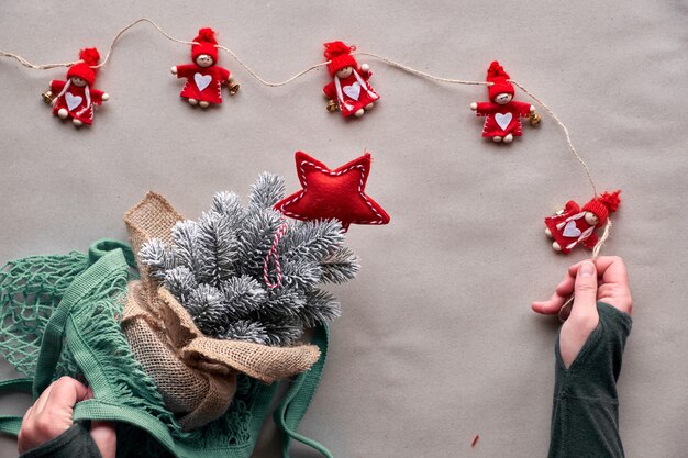 Alternatives grünes Weihnachten, Neujahrskonzept. Flache Lage, Draufsicht auf Bastelpapier. Feiern Sie mit einem falschen Baum, ohne einen echten Baum zu töten! Plastikweihnachtsbaum in Netztasche, umweltfreundliches Spielzeug ohne Plastik.