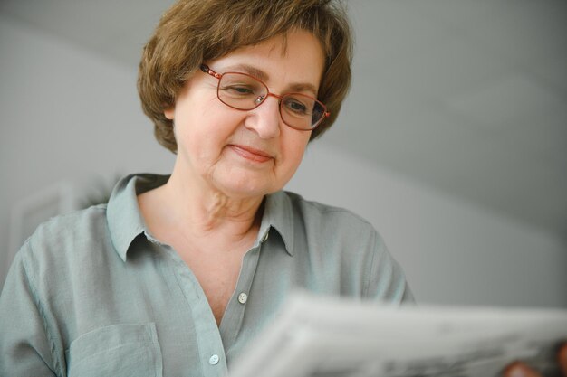 Alters- und Personenkonzept Glückliche Seniorin, die zu Hause Zeitung liest