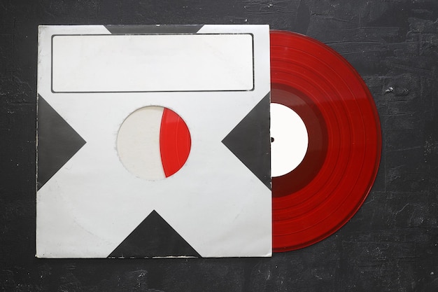 Alterte schwarze Papierhülle und rote Vinyl-LP-Platte, isoliert auf einem steinernen Hintergrund