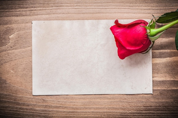 Altes Blatt Papier und rote Rose auf Holzbrett