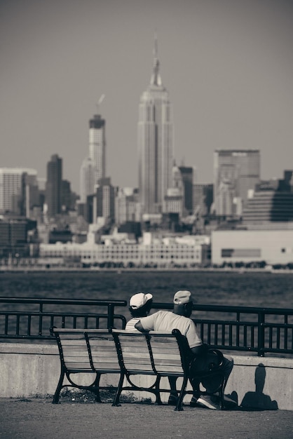 Altes Ehepaar sitzt am Wasser mit Blick auf die Stadt Manhattan