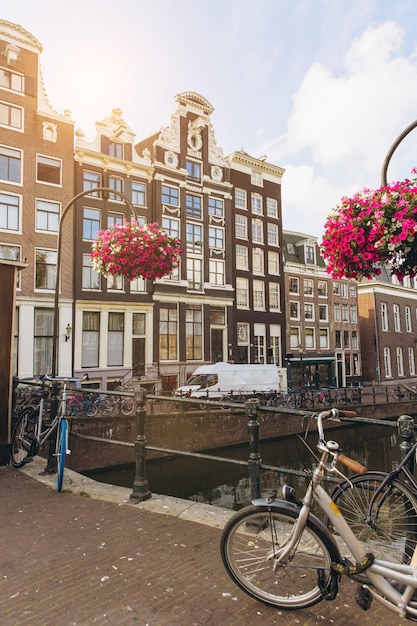 Altes Fahrrad auf der Brücke in Amsterdam Niederlande gegen einen Kanal im Sommer sonniger Tag Postkarte ikonische Ansicht Tourismuskonzept