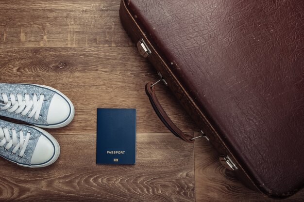 Altes Gepäck, Reisepass, Turnschuhe auf Holzboden