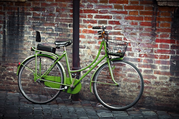 Altes grünes Retro-Fahrrad mit Korb gegen Schmutzwand in Ravenna, Italien