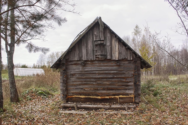 Altes Holzgebäude des Badehauses im Dorf auf dem Feld mit Herbstlaub im Herbst. Traditionelles Äußeres im russischen Stil.