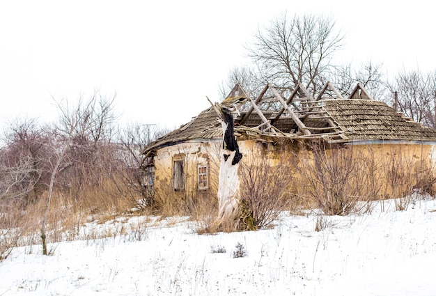 Altes Lehmhaus im ukrainischen Dorf. Ruiniertes Lehmhaus im Schnee.