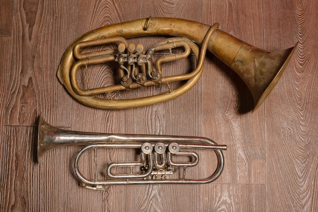 Foto altes messingblasinstrument und horn auf einem hölzernen hintergrund.