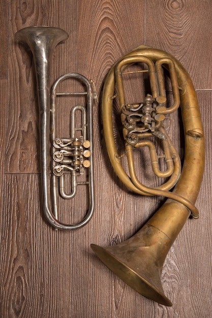 Altes Messingblasinstrument und Horn auf einem hölzernen Hintergrund.