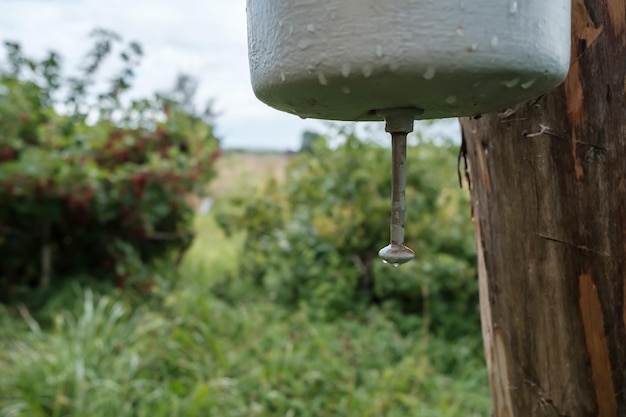 Altes Metallwaschbecken, das an einem Holzpfosten in einem Innenhof auf dem Land befestigt ist