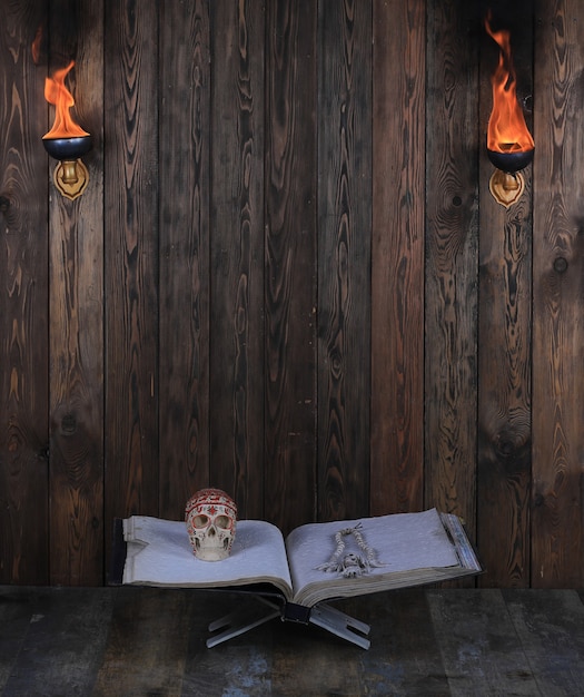 altes offenes Buch mit Totenkopf auf Holzuntergrund