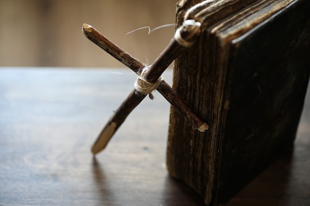 Altes religiöses Buch und Holzkreuz auf dem Hintergrund einer Holz- und Sackleinen