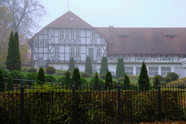 Altes Retro-Haus mit rotem Ziegeldach im preußischen Stil mit Grünflächen im Nebel