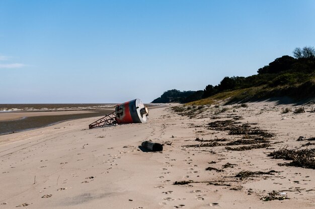 Altes rotes und schwarzes Leuchtfeuer gestrandet am Strand Kiyu San Jose Uruguay