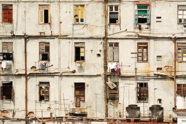 Altes, schäbiges Wohngebäude in den Slums der Stadt Havanna mit trocknender Kleidung, die an den Fenstern hängt