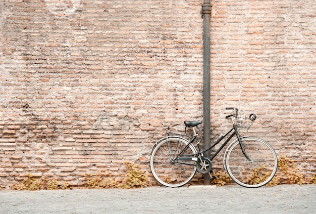 Altes schwarzes fahrrad gegen eine backsteinmauer