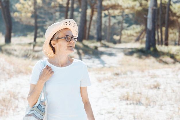 Altes Seniorenporträt im Freien mit Kopienraum mit Brille während eines Ausflugstages am Strand bei kaltem Wetter. Neue Gewohnheiten, Vortrag und Bewegung für ein gesundes Leben in diesem Eintrittsjahr neues Leben.