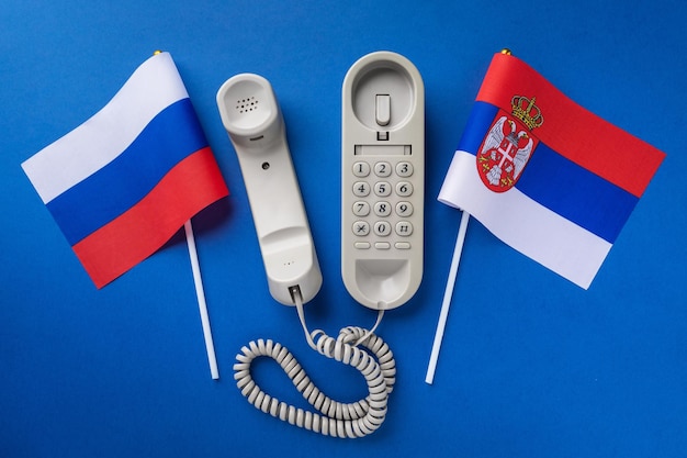 Altes Telefon und zwei Flaggen auf blauem Hintergrund
