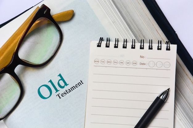 Altes Testament-Cover in der Bibel mit Notizbuch, Stift und Brille