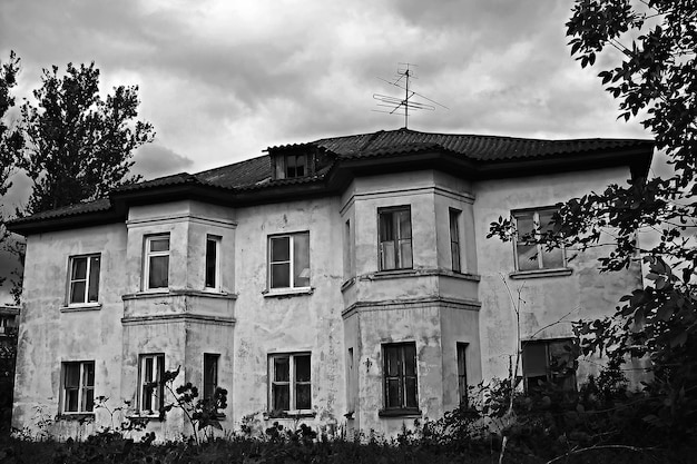 altes und gruseliges Haus auf dramatischem Hintergrund des bewölkten Himmels Schwarz und Weiß