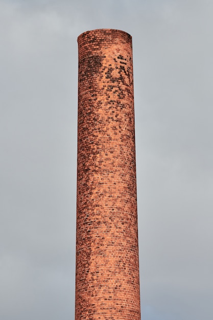 Altes Ziegelsteinfabrikrohr auf grauem Himmel