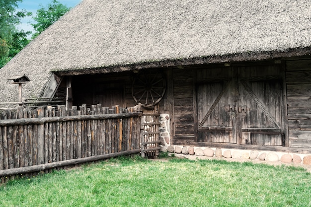 Altmodisches Holzhaus im Dorf des 19. Jahrhunderts mit langem Holzzaun.