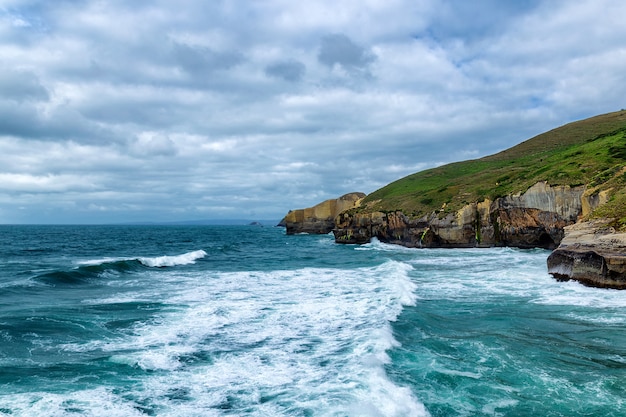 Alto acantilado arenoso y olas del océano Pacífico en Tunnel Beach, Nueva Zelanda