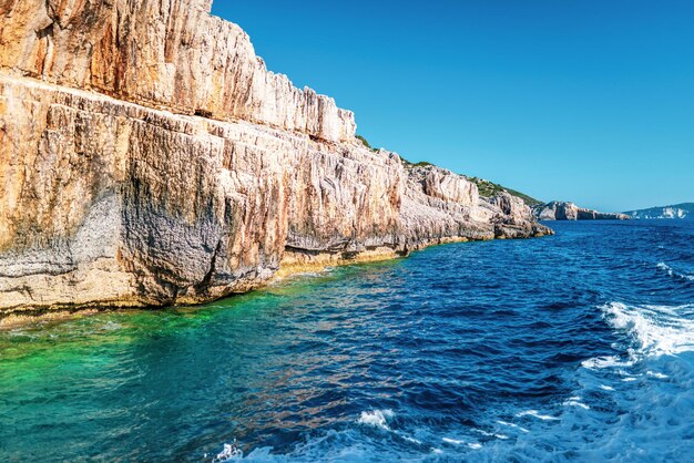 Alto acantilado empedrado en la playa de mar de la isla de Corfú al atardecer