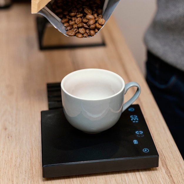 Foto alto ângulo de barista masculino pesando grãos de café usando balança