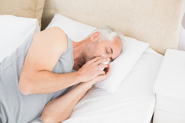 Alto ângulo de um homem que sofre de frio na cama