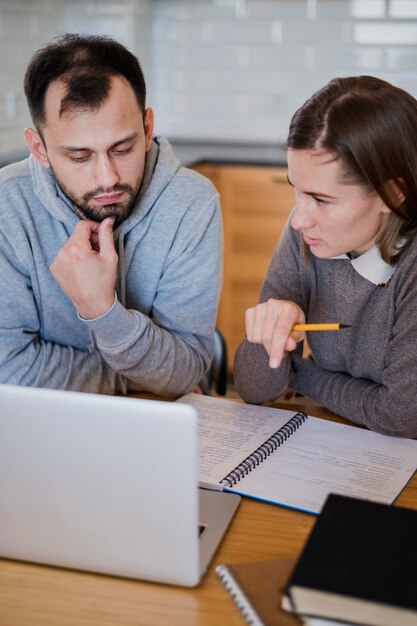 Alto ângulo do tutor dando aulas para o aluno em casa