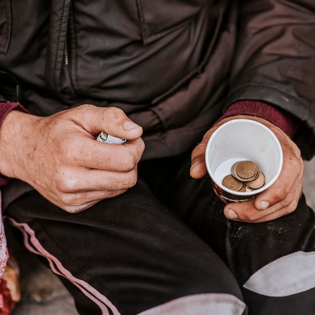 Foto alto ángulo de hombre sin hogar con taza y monedas