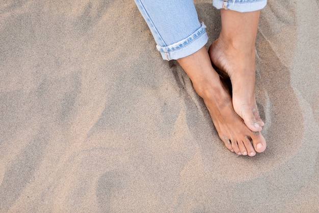 Alto ángulo de pies de mujeres en la arena de la playa