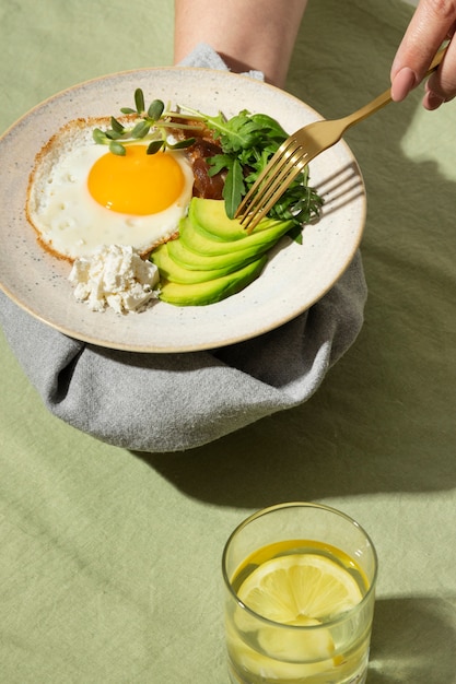 Alto ángulo de plato con comida cetogénica y un vaso de agua con limón