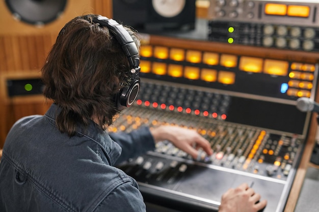 Alto ángulo en el productor de música que opera la estación de trabajo de audio en el espacio de copia de estudio de grabación profesional