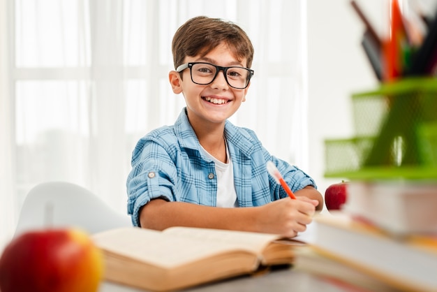 Foto alto ángulo smiley boy con gafas estudiando