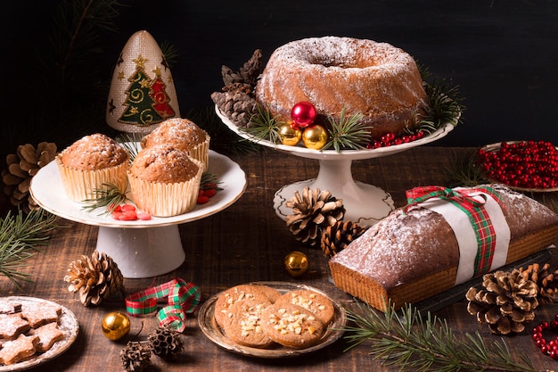 Alto ángulo de surtido de postres navideños con piñas y frutos rojos