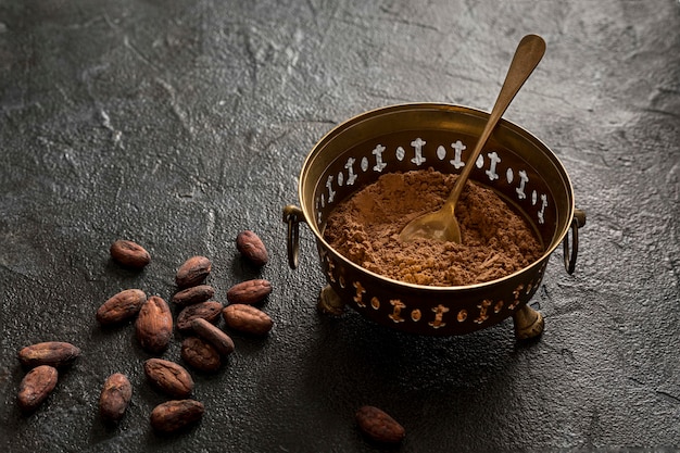 Alto ángulo del tazón con cacao en polvo y granos de cacao