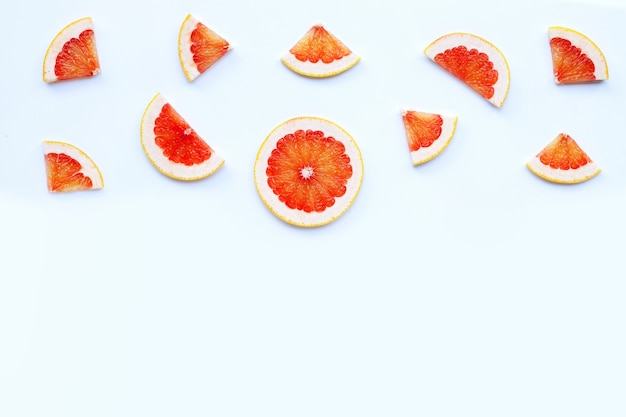 Alto contenido de vitamina C. Jugosas rodajas de pomelo sobre superficie blanca.