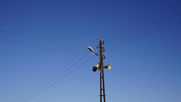 Alto-falantes no céu azul e poste elétrico