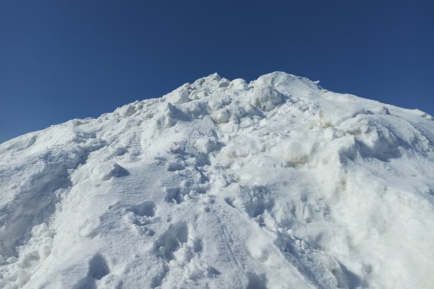 Alto montón de nieve blanca en un día soleado de invierno.