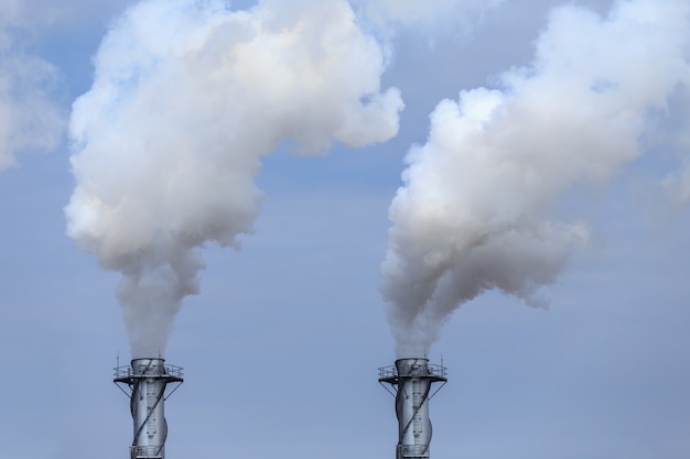 Foto alto vapor industrial blanco en fábrica en el cielo azul