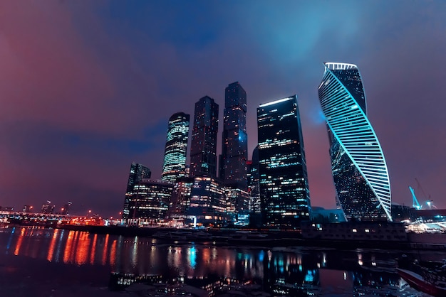 Altos arranha-céus modernos da cidade de Moscou, com iluminação e reflexo no rio